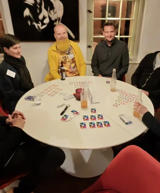 Runde am Tisch, die Karten liegen aus